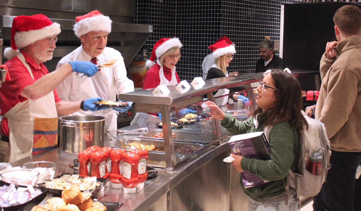 faculty serving pancakes to students in law school cafe